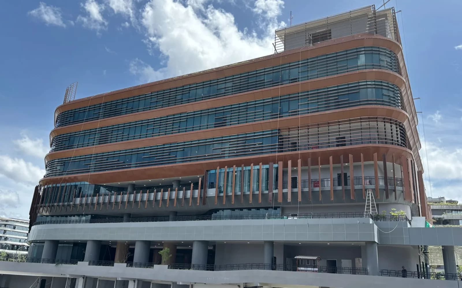 Curtain wall dan fin vertikal pada gedung kantor berlantai banyak di IKN, dilihat dari sisi jalan.