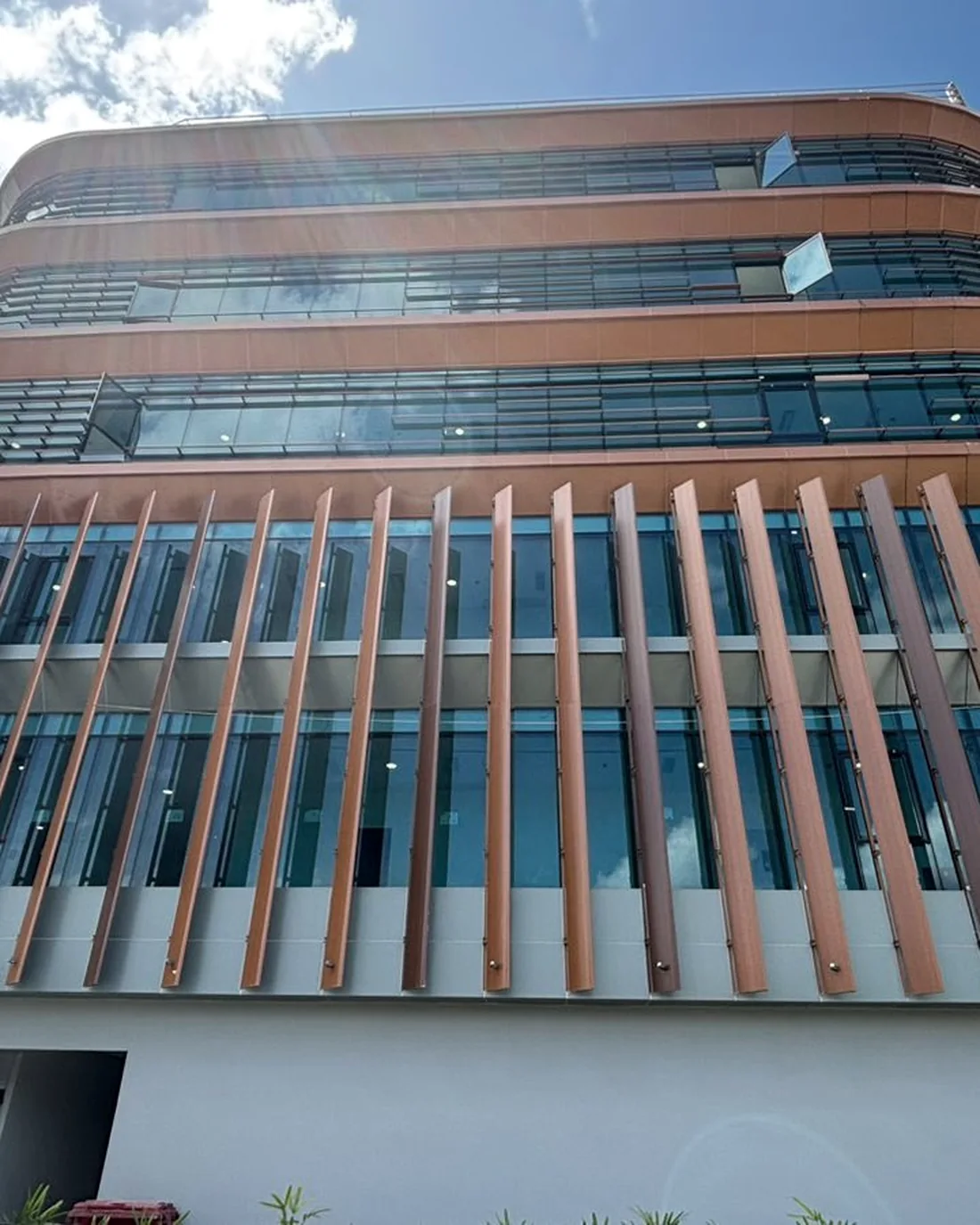 Deret fin vertikal aluminium di depan bidang kaca gedung kantor di IKN.